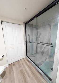 Remodeled walk-in shower with sliding glass doors and updated wall panels
